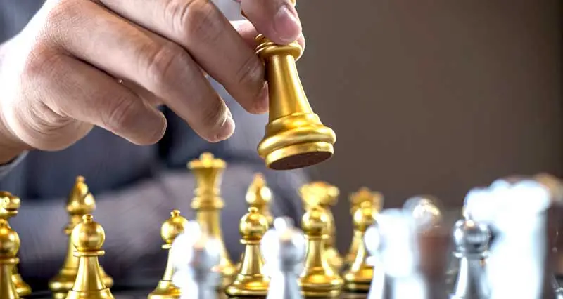 Schachspieler spielt mit goldenen Schachfiguren
